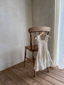 Gesmokt zomer kinderjurkje in lichte creme kleur met gesmokt lichaam en volants aan de onderkant