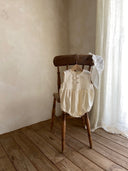 schattig ivory kleurig rompertje met strikjes hangend aan stoel in de categorie babykleding en kinderkleding