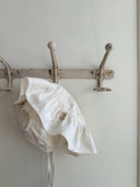 Aimee bloomer rokje van katoen in creme met geborduurde bloemen en elastische tailleband met verstelbare schouderbandjes hangend voor/onder aanzicht