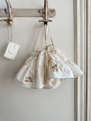 Aimee bloomer rokje van katoen in creme met geborduurde bloemen en elastische tailleband met verstelbare schouderbandjes hangend vooraanzicht close up