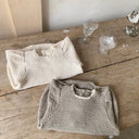 amy rompertje voor baby's en dreumes van 12 en 18 maanden van gewafelde katoenen stof met pofmouwtjes kanten randje langs de hals en knoopjes onderaan liggend opgevouwen vooraanzicht