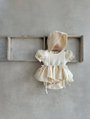 Baby meisje Mia romper jurkje van katoen en mousseline, pofmouwen, volumineus rokje en strikjes voor baby en dreumes in creme (3 - 24 maanden) vooraanzicht