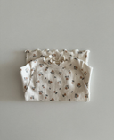 Baby meisje Celina top van geribbeld zacht katoen in creme met bloemenprint en gerimpelde afwerking opgevouwen bovenaanzicht