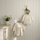 Baby meisje Maya romper van geweven stof met kanten kraagje en ballonmouwtjes maat 62 - 86 ( 0 - 18 maanden) hangend aan muur vooraanzicht 