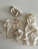 Baby meisje Marie wikkel jurkje/overjurkje schortje van opengewerkt katoen met volantkraag , strik en geborduurde bloemetjes in creme - one size 86/92/98 bovenaanzicht gestyled met celina legging en top met bloemetjes