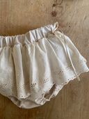 Baby meisje Lilly bloomer rokje van katoen  met geborduurde bloementjes en strikjes in creme kleur maat S 62/68/74 (3 - 10 maanden) en maat M 80/86 (10 - 18 maanden) close up liggend 