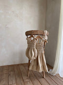 Baby meisje Diana romper van stevig katoen met gesmokt bovenlijfje - Beige (3 - 18 maanden) samen met june dress hangend vooraanzicht