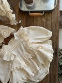 Baby meisje Elisabeth romper jurkje van katoen, lange mouwen en volants in creme 6 - 18 maanden liggend schuin bovenaanzicht - stijlvolle baby en kinderkleding