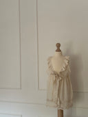 Baby meisje Marie wikkel jurkje/overjurkje schortje van opengewerkt katoen met volantkraag , strik en geborduurde bloemetjes in creme op pop