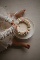 Baby meisje Celina top van geribbeld zacht katoen in creme met bloemenprint en gerimpelde afwerking - close up baby met handjes in taart