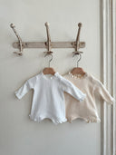 Baby meisje Sera Newborn pakje/geboortepakje van wafel katoen met kanten randjes en bijpassend mutsje maat 62/68 en 74/80 creme en wit vooraanzicht hangend aan kapstok